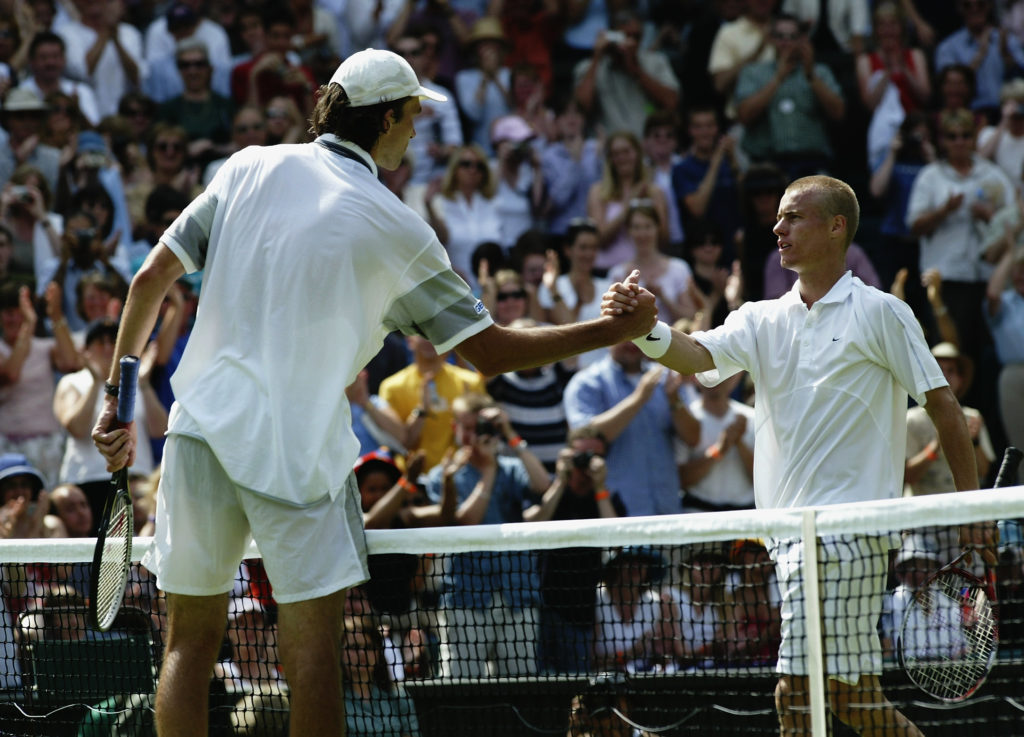 Ivo Karlovic of Croatia shakes hands at the net after beating defending champion Lleyton Hewitt of Australia