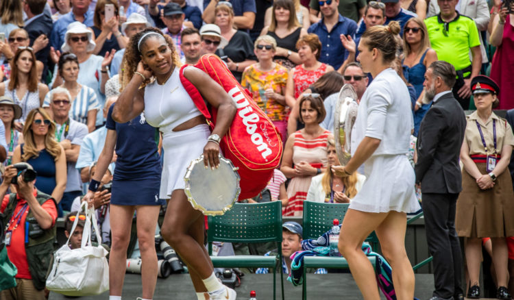 Serena Williams of the United States walks with Simona Halep of Romania as they hold their trophies after the Ladies Singles Final on Centre Court ...