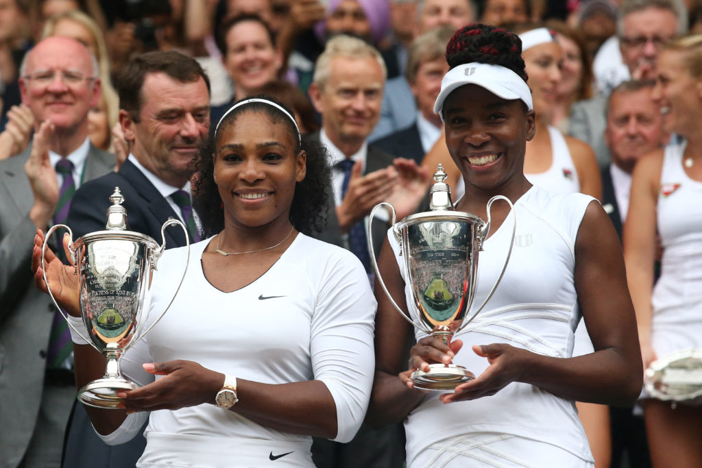 Serena Williams and Venus Williams celebrate with the doubles titles after winning Wimbledon in 2016.