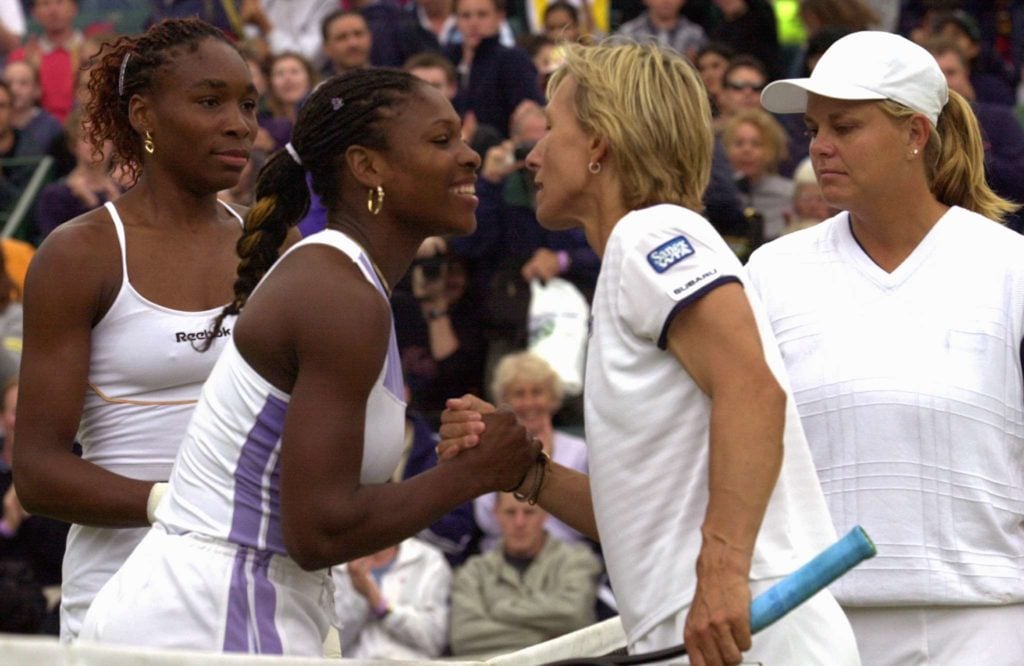 Venus Williams (L) watches her sister Serena (2nd