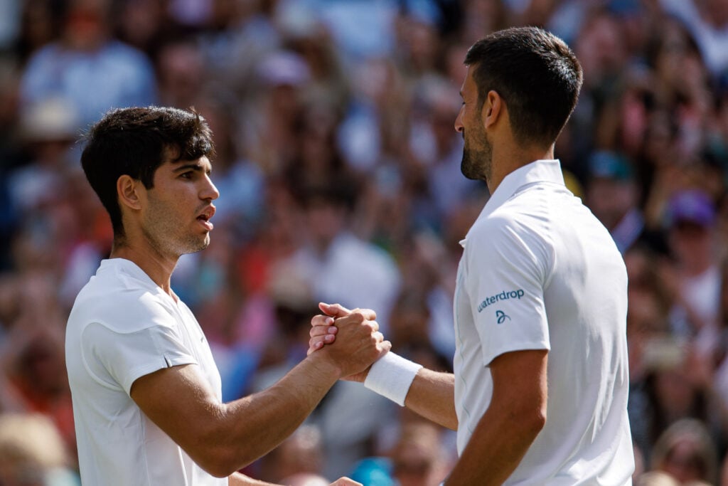 Carlos Alcaraz and Novak Djokovic shake hands at Wimbledon 2024.