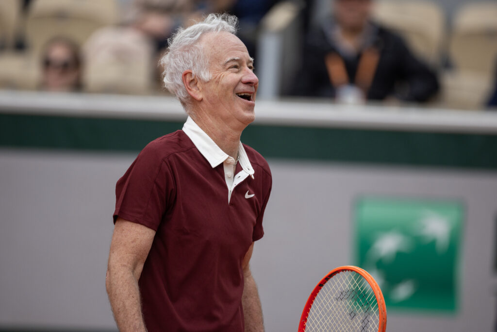 John McEnroe laughing while playing doubles in the legends competition at the 2025 French Open