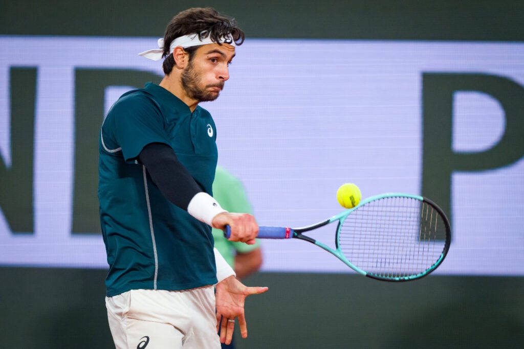 Lorenzo Musetti hits a one-handed backhand against Carlos Alcaraz at the 2025 French Open