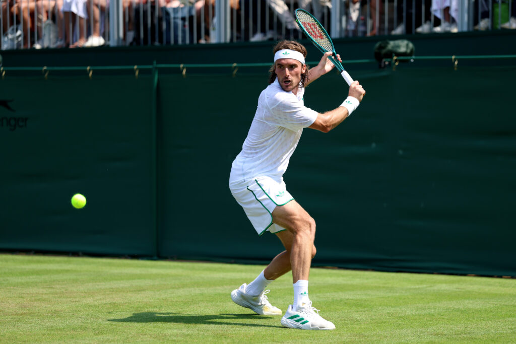 Stefanos Tsitsipas playing a backhand at Wimbledon in 2025.