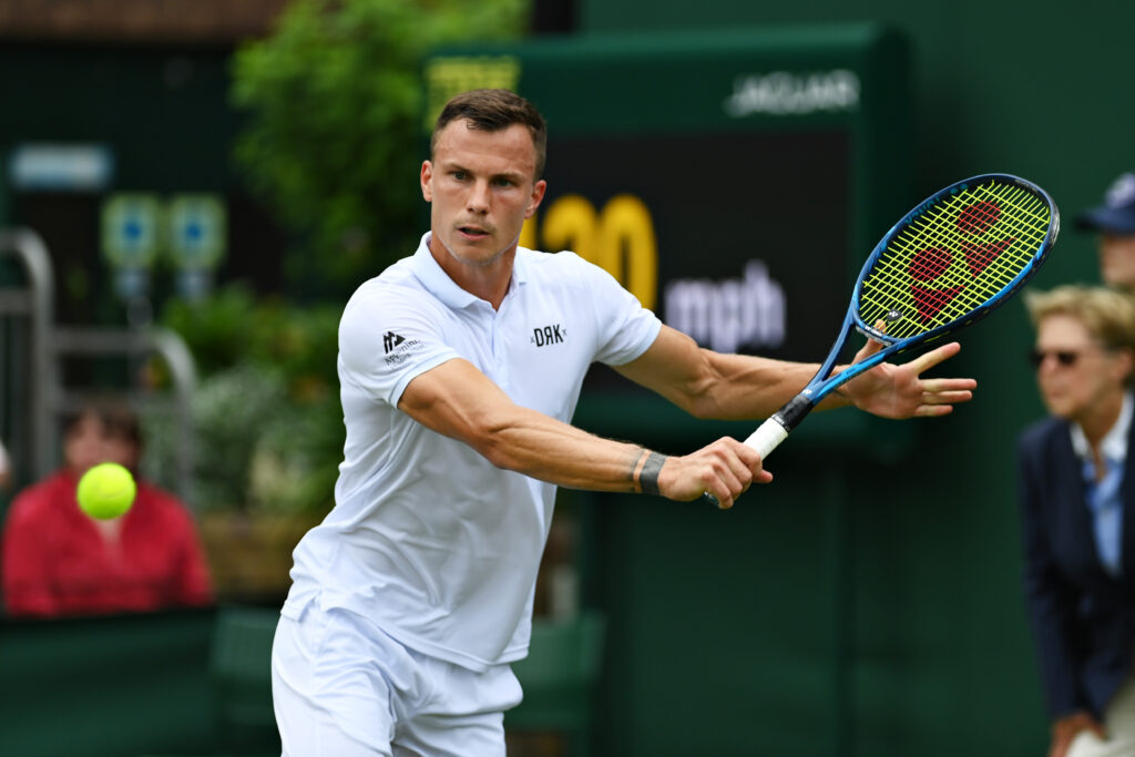 Marton Fucsovics of Hungary plays a backhand in his Men's Singles First Round match against Jannik Sinner of Italy during Day One of The Championships - Wimbledon 2021 at All England Lawn Tennis and Croquet Club.