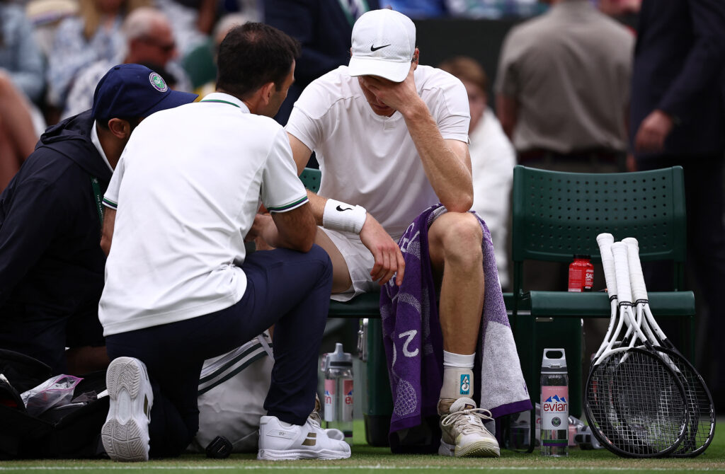 Jannik Sinner talks to staff during a medical time-out in his match against Russia's Daniil Medvedev during their men's singles quarter-final tennis match on the ninth day of the 2024 Wimbledon Championships at The All England Lawn Tennis and Croquet Club in Wimbledon.