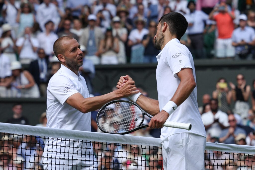 Dan Evans and Novak Djokovic shake hands at the net after their clash at Wimbledon.