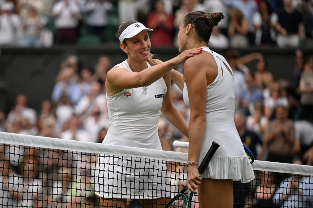 Aryna Sabalenka and Elise Mertens embrace at the net at Wimbledon 2025