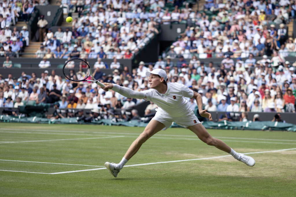 Jannik Sinner stretches to return Ben Shelton's serve at Wimbledon in 2025