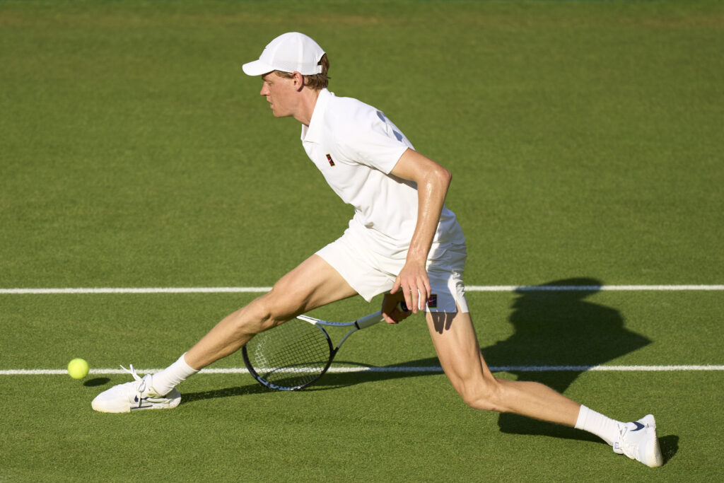 Jannik Sinner slides to play a point against Novak Djokovic in the 2025 Wimbledon semifinal