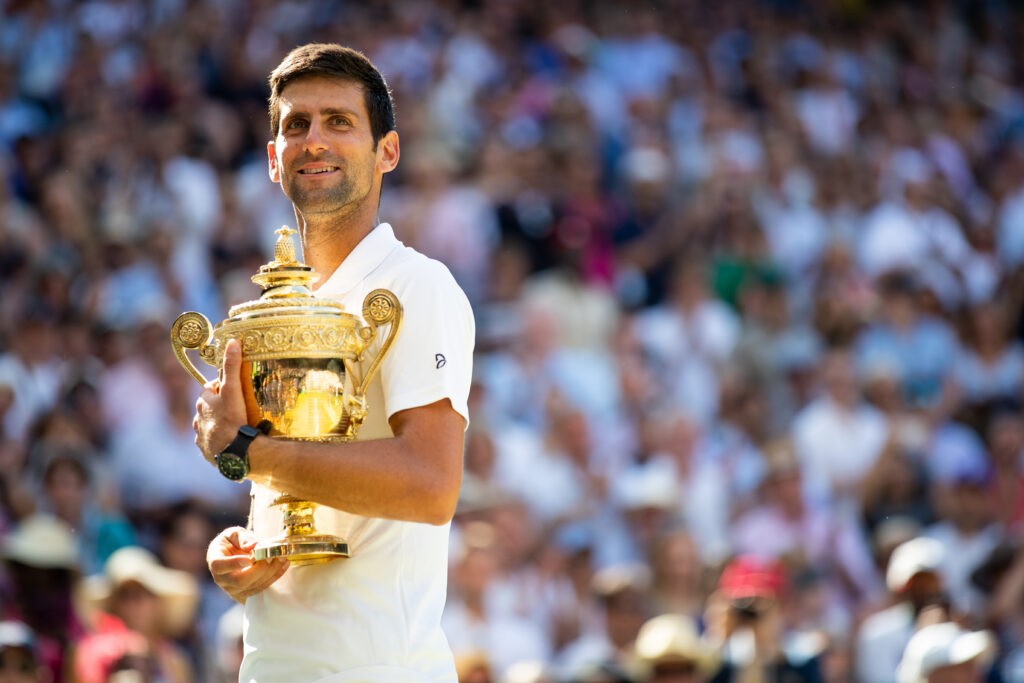 Novak Djokovic holding the 2018 Wimbledon title.