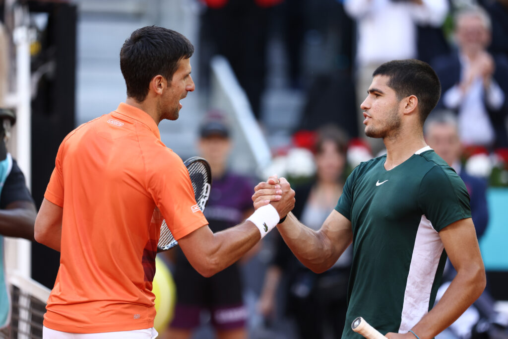 Novak Djokovic and Carlos Alcaraz shake hands at the net after their first career clash at the Madrid Open in 2022.