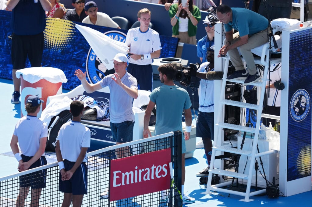Jannik Sinner meets with Carlos Alcaraz and the umpire after retiring from the Cincinnati Open final.