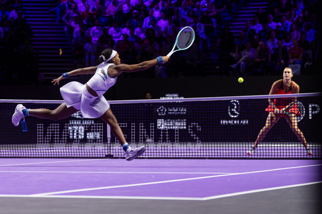 Coco Gauff stretches for a volley at the net as Aryna Sabalenka looks on