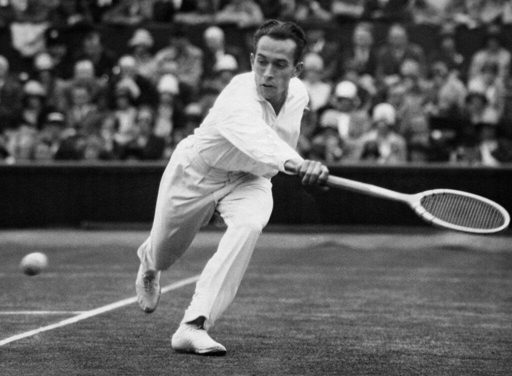 Henri Cochet reaches for a backhand during a tennis match.