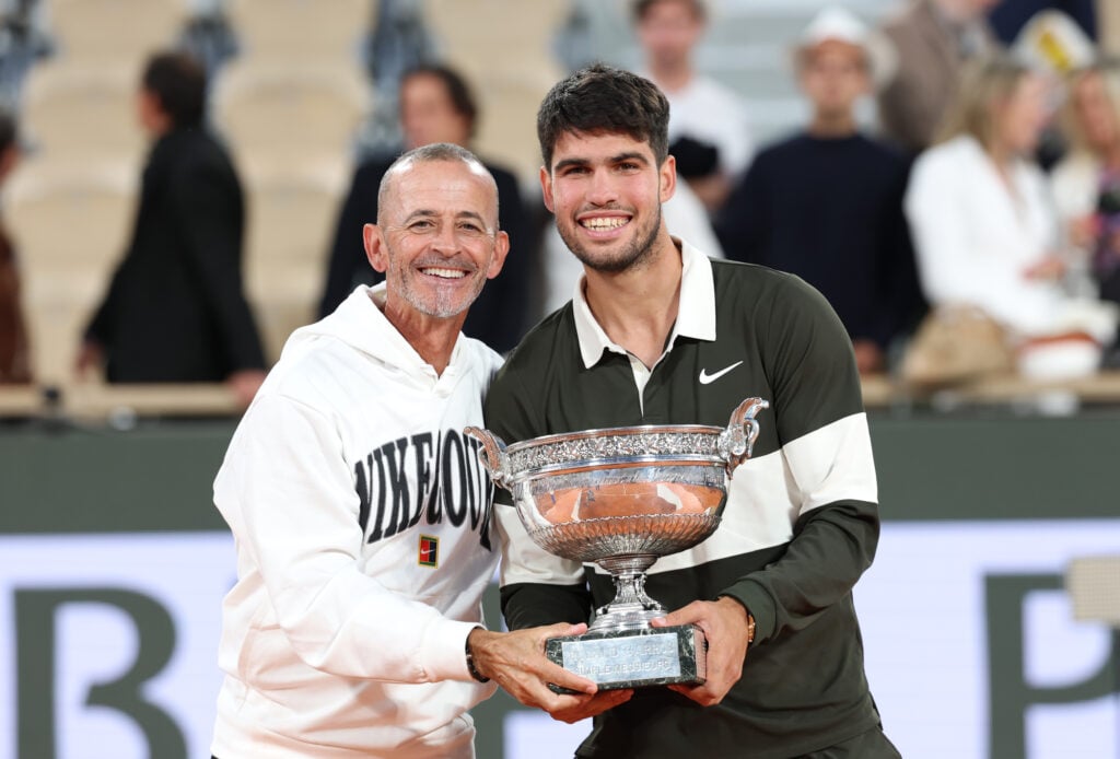 Carlos Alcaraz poses with the French Open trophy alongside coach Samuel Lopez after beating Jannik Sinner in the 2025 final.