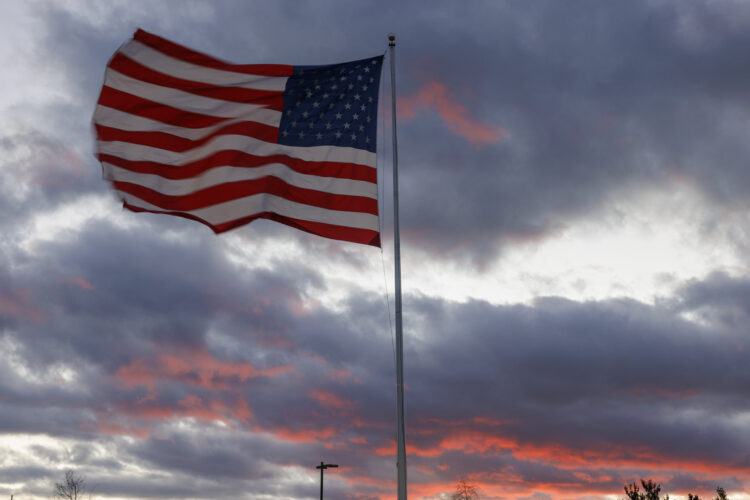 BLOOMINGTON, INDIANA - NOVEMBER 26: As the American flag waves in a cold wind sunset bathes the skies in crimson on Nov. 26, 2025, in Bloomington, ...