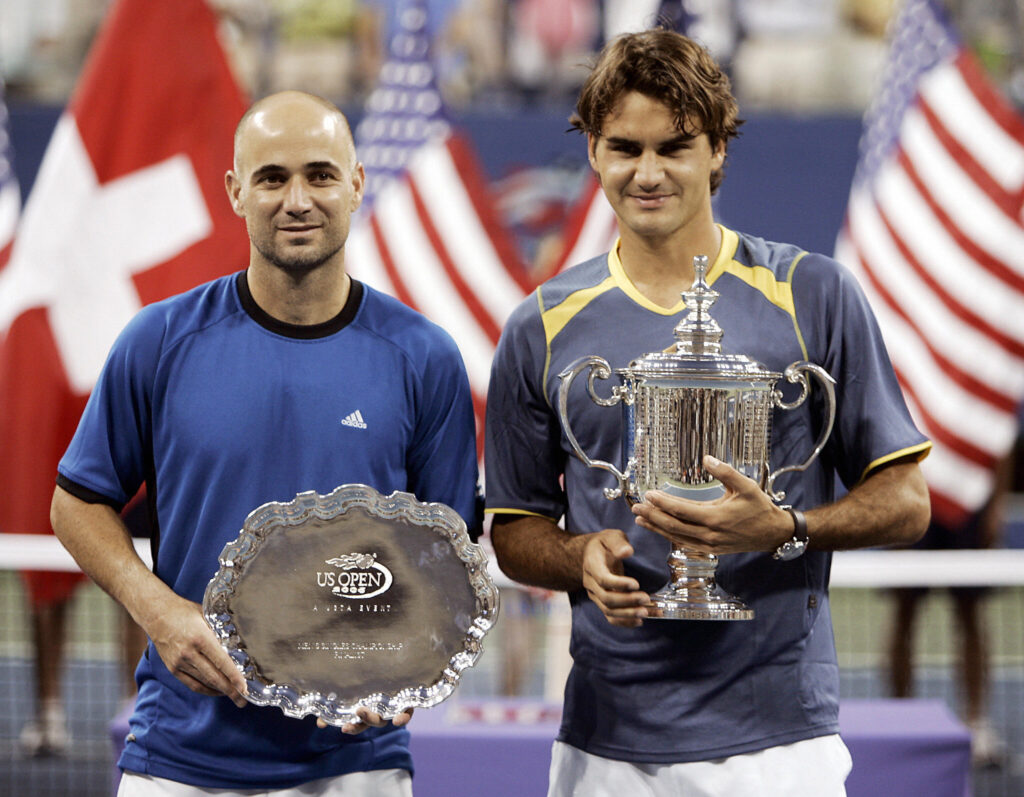 Roger Federer and Andre Agassi holding their trophies after the 2005 US Open final.