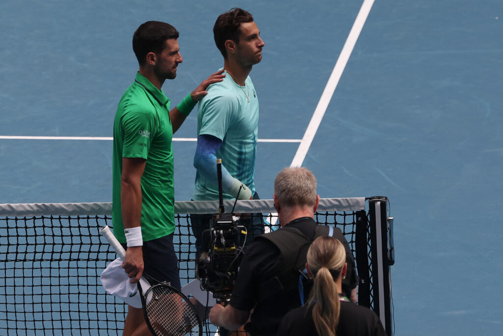 Novak Djokovic puts his arm on Lorenzo Musetti's shoulders