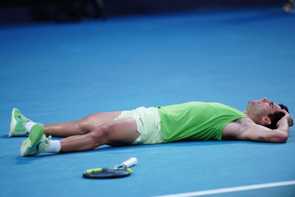 Carlos Alcaraz falls to the floor after winning against Alexander Zverev.