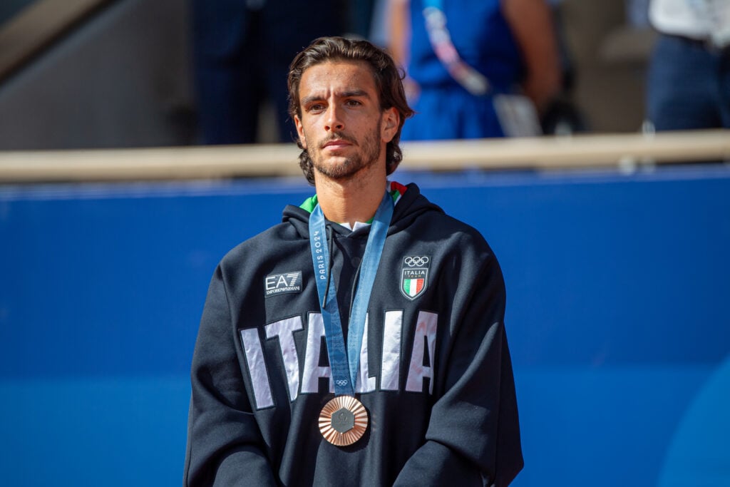Lorenzo Musetti poses with an Olympic bronze medal.