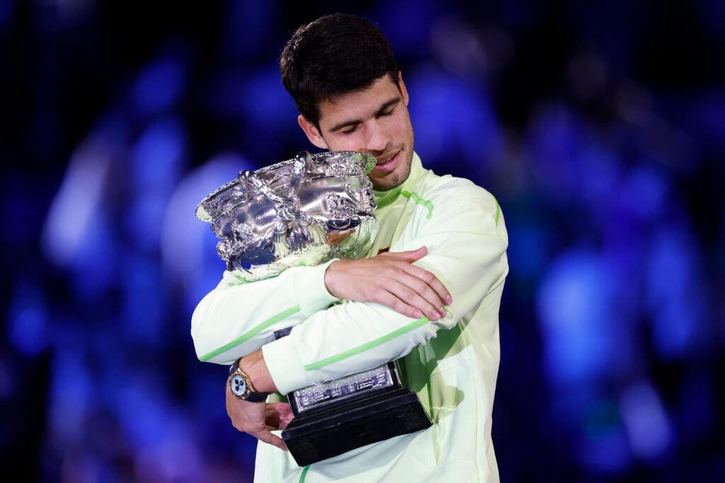 Carlos Alcaraz hugs the Australian Open trophy after beating Novak Djokovic in the 2026 final.