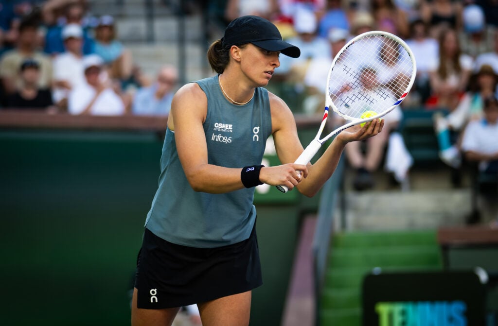 Iga Swiatek prepares to serve against Elina Svitolina at Indian Wells in 2026.