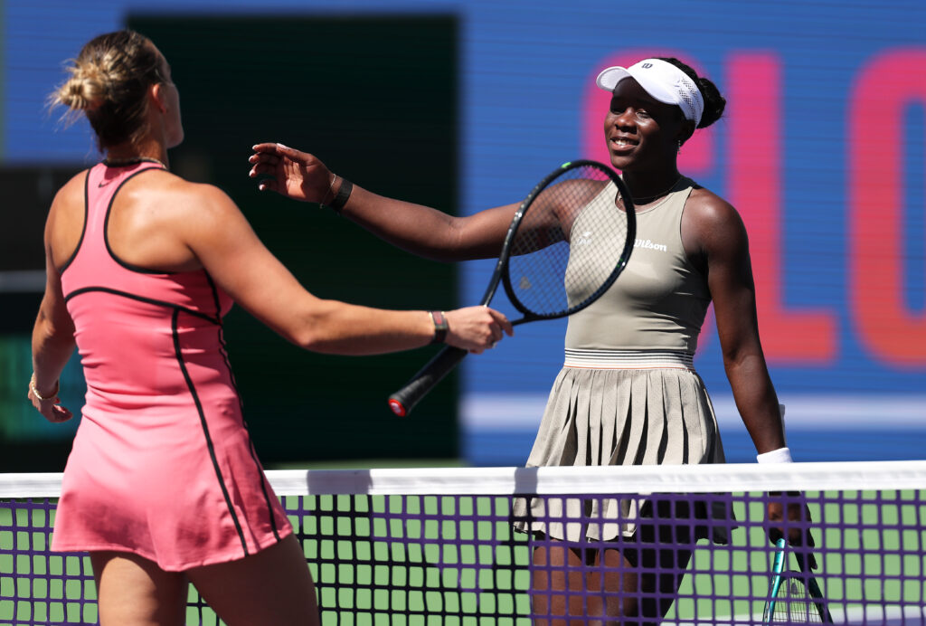 Aryna Sabalenka and Victoria Mboko meet at the net.