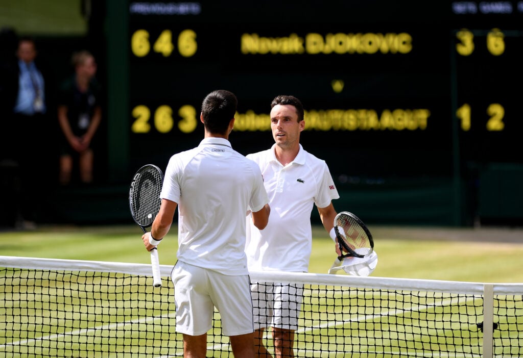 Novak Djokovic and Roberto Bautista Agut embrace after their match at Wimbledon in 2019.