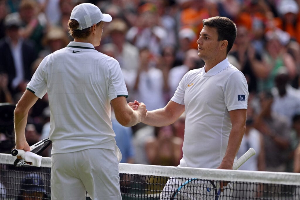 Jannik Sinner and Miomir Kecmanovic shake hands.