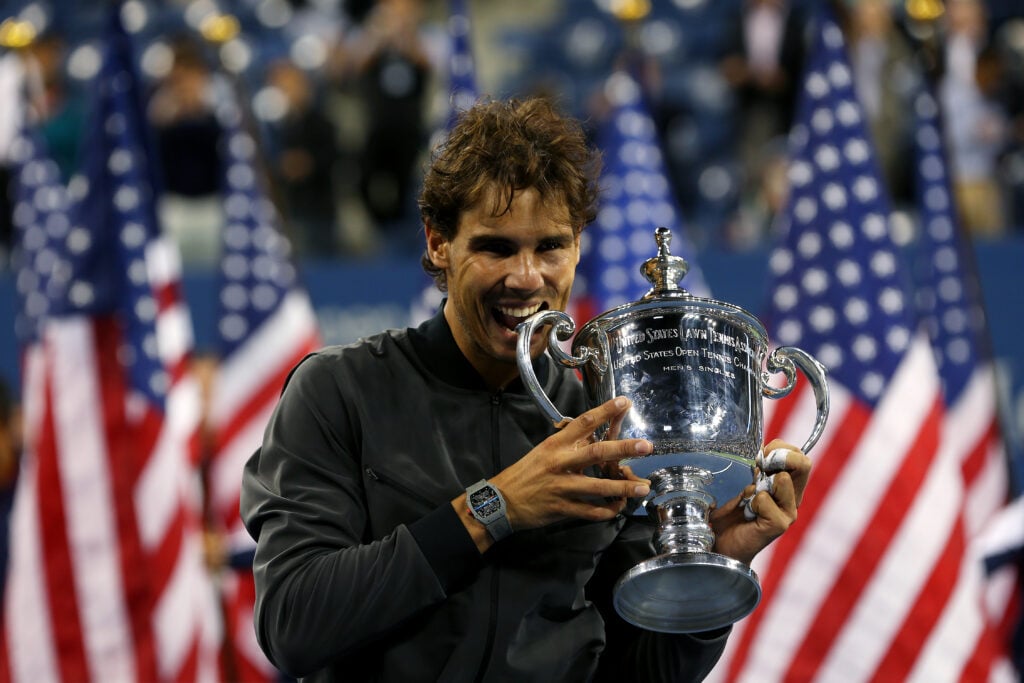 Rafael Nadal bites the 2013 US Open trophy.